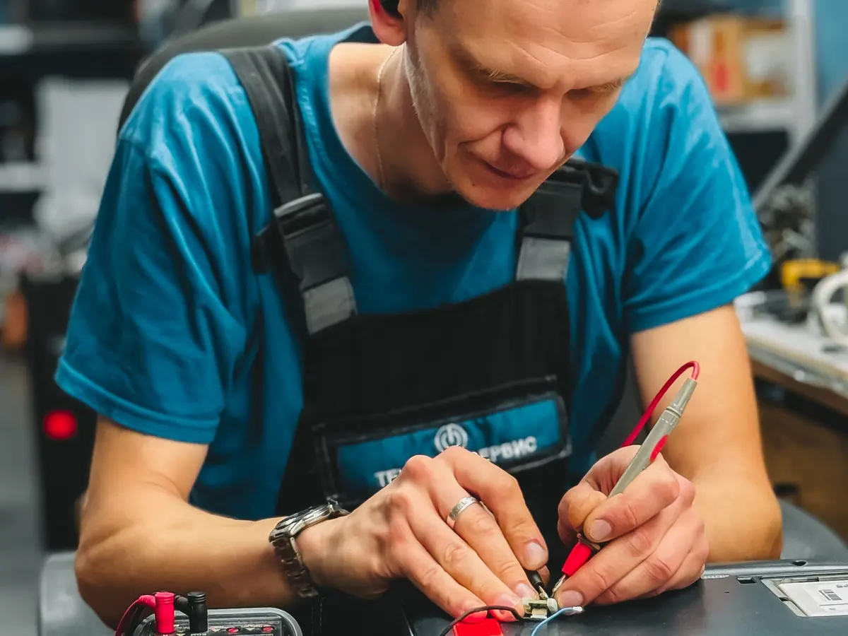 Técnico midiendo con un multímetro la placa de una computadora durante el diagnóstico