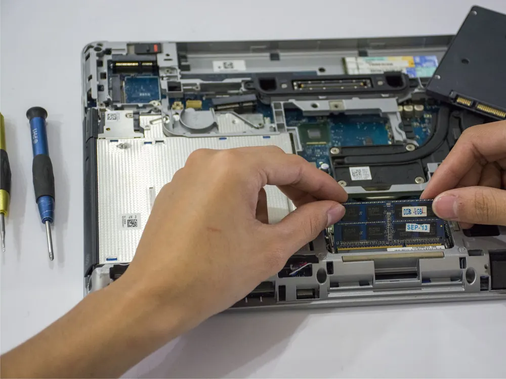 Técnico instalando una memoria RAM en una laptop durante una reparación en Durán